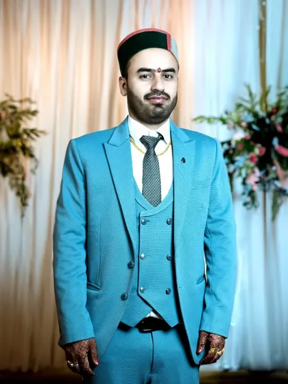 A full-length formal portrait of the groom. This classic wedding shot captures the entire look, from the tailored suit to the traditional cap.