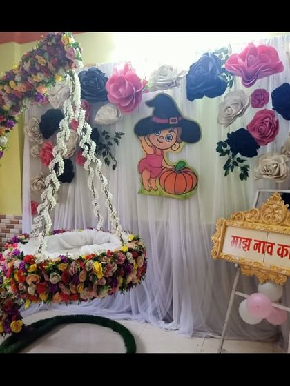 A clearer view of the unique Halloween-themed naming ceremony decoration, showing the paper flower backdrop and the decorated cradle.