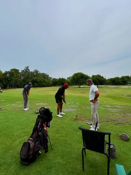 A coach offers some tips to a player on the grass tee area, a perfect example of our hands-on approach.