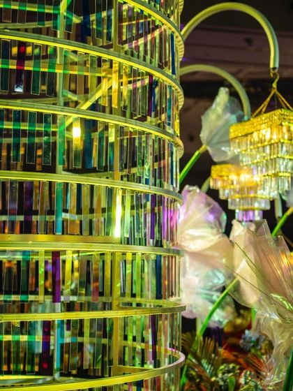 A detailed view of the kinetic chandelier sculpture, showing the layers of iridescent panels that catch and reflect the stage lights.