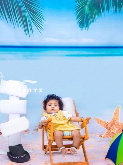 A fun and sunny beach-themed studio photoshoot. We create a seaside escape with a sand and ocean backdrop, a deck chair, and beach props like a starfish and umbrella, perfect for a vacation vibe any time of year.