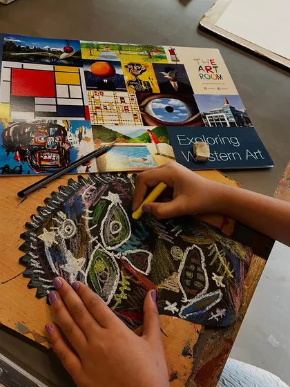 A student uses oil pastels to create a powerful, expressive face inspired by the neo-expressionist work of Jean-Michel Basquiat.