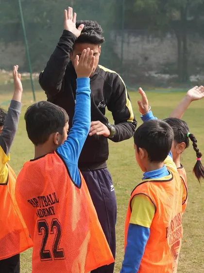 A coach high-fiving his players. We offer expert coaching that meets international standards, focusing on long-term player growth.