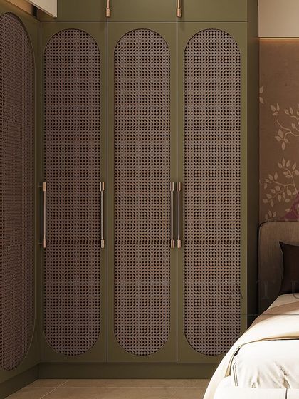 A corner wardrobe in olive green with unique rattan-paneled doors, adding texture and a touch of bohemian chic to the bedroom.