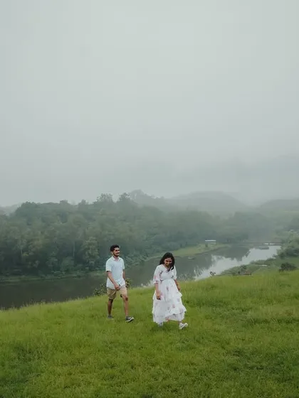 Another beautiful shot of the couple walking in the expansive green landscape, capturing the serene and peaceful vibe of their love story.