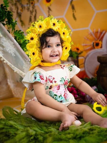 A happy toddler wearing a sunflower bonnet in a cheerful bee-themed setting.