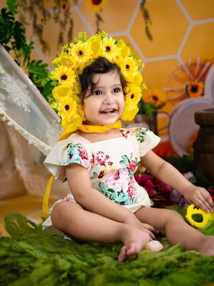A happy girl in her sunflower crown. This theme is perfect for a sunny and joyful first birthday or toddler photoshoot.