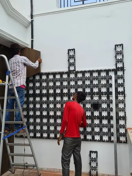 A closer view of the installation in progress. One of my team members is on a ladder, fixing the final sections of the grid to the wall. This durable framework is essential for supporting the weight of the plants and the irrigation system.