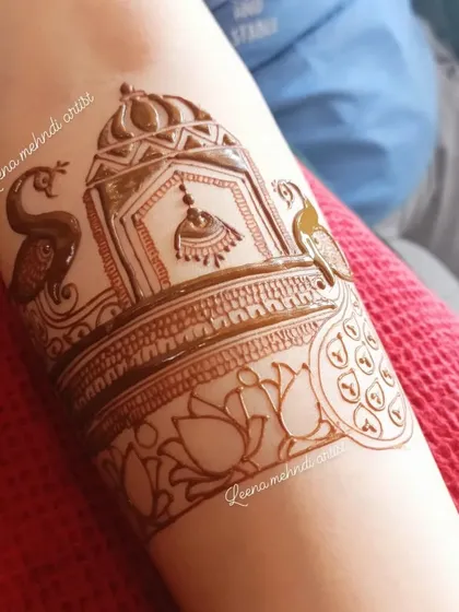 The finished heavy start-up piece for a forearm. The design features a jhumka in a dome, flanked by peacocks and sitting atop a lotus band.