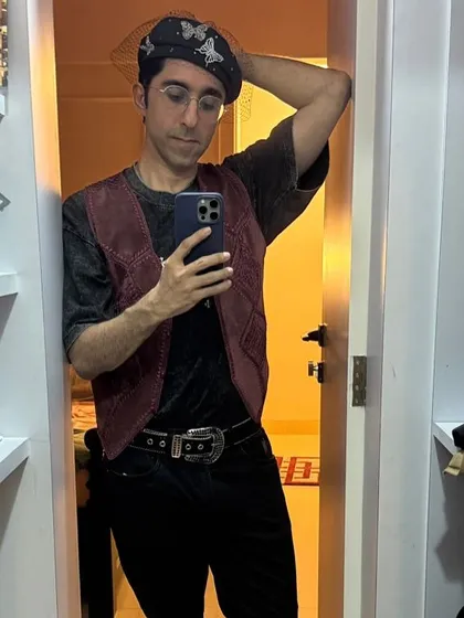 A mirror selfie from our client showing off his styled look. The combination of the burgundy vest, acid-wash tee, and statement belt is effortlessly cool.