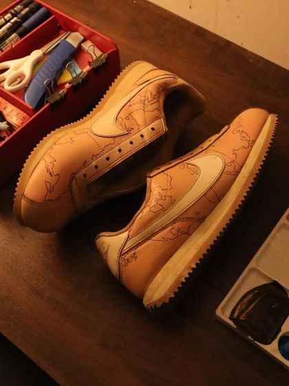 The Nike Cortez with the world map design, sitting on my work desk. This behind-the-scenes shot shows the sneakers ready for their final floral details.