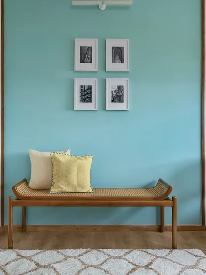 A cozy corner in the 'Malhar' home office, featuring a wooden bench with cane detailing set against a calming blue accent wall.