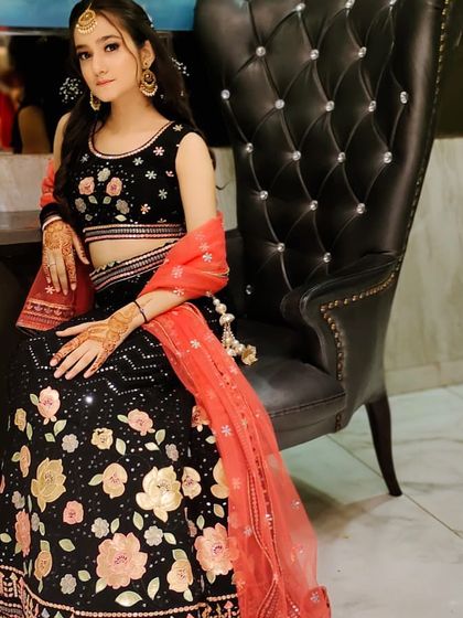 A unique black lehenga with peach and gold floral appliqué work. This is a modern and romantic rental outfit for an engagement or reception.