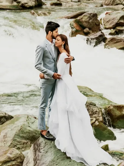 A couple shares a tender moment on the rocks by a rushing river in Sonmarg, Kashmir. This destination pre-wedding photo combines romance with the raw power of nature.