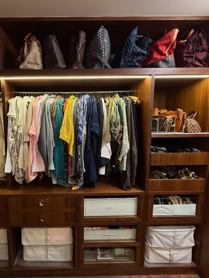 The "her" side of the closet, featuring colorful garments and a dedicated section for handbags, organized for style and accessibility.