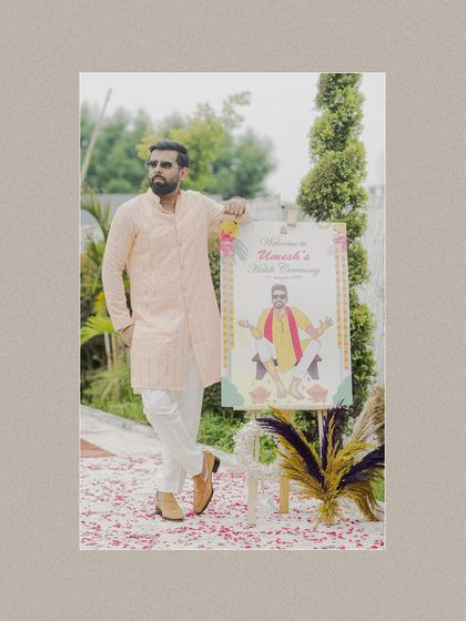 The groom poses coolly next to a welcome sign for his Haldi ceremony, setting a fun and personalized tone for the event.