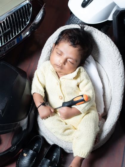 This little rider is ready for the open road. The setup includes a helmet, tool kit, and a classic toy car, creating a complete story for a future automobile enthusiast.