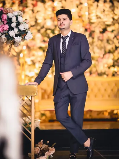 This client is the picture of sophistication. His navy blue suit and patterned tie are perfectly complemented by a sharp haircut and a subtle makeup application that highlights his features.