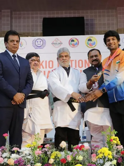 Awarding a medal to a young champion at the KIO National Championship, alongside other senior officials of the federation.
