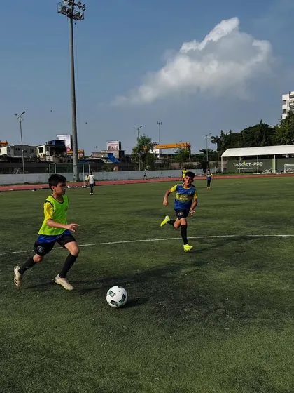 Two players chase after the ball during a practice match on a sunny day. This photo embodies the idea that on our pitch, players are always chasing a better version of themselves.