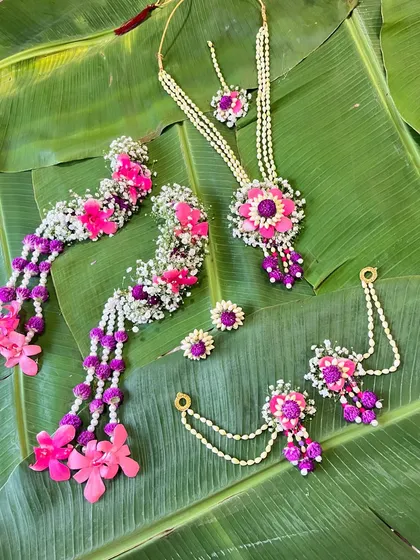 The full pink and purple Haldi jewellery set, including the necklace, maang tikka, earrings, and hath phool. This style is popular for brides who want a pop of color.