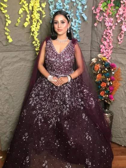 Make heads turn at your reception or cocktail party with this deep purple sequined gown. The intricate silver sparkle work catches the light beautifully, and the attached cape adds a touch of modern drama. It’s a glamorous look available for rent for your special night.