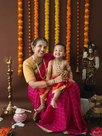 A full view of the simple yet beautiful Janmashtami setup, featuring marigold garlands, a Krishna statue, and traditional brass lamps.