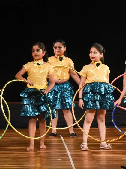 The hoop dance troupe in a synchronized formation. The matching costumes and colorful hoops create a visually appealing and well-rehearsed performance piece.