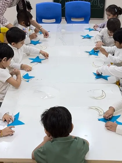 An overhead view of the Eid craft session. The classroom is a hub of focused creativity as the children work on their projects.