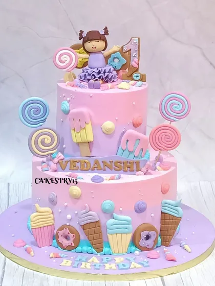 A whimsical two-tier Candyland cake for a first birthday. This 5kg lavender-colored masterpiece is adorned with a fondant doll, lollipops, donuts, and ice cream cones.
