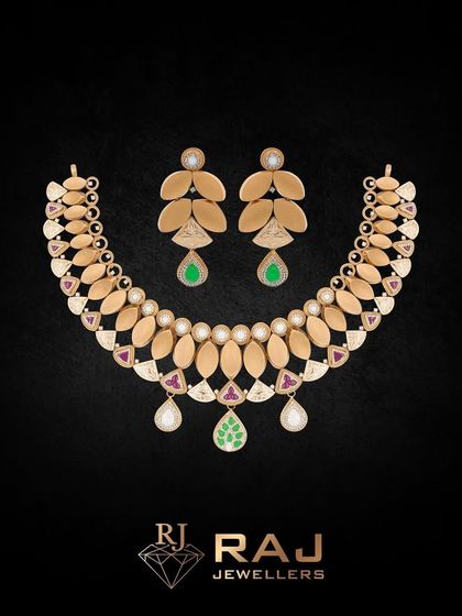 This Revaj necklace and earring set is crafted with matte gold leaves and accented with polki, rubies, and pearls. The design is elegant and understated, with drops of green gemstone adding a subtle touch of color.