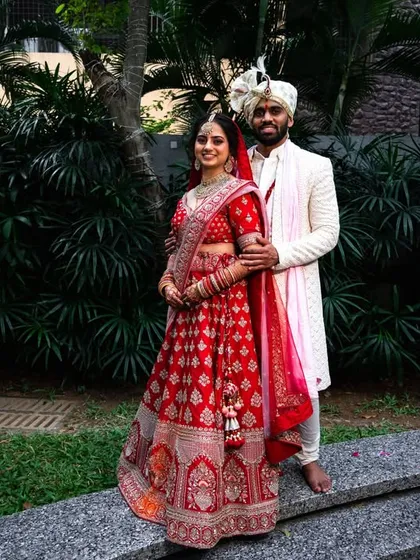 A full-length portrait showcasing the couple's beautiful wedding outfits against a lush green background.