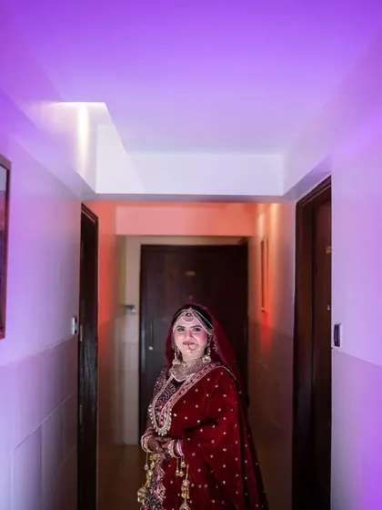 A full-length portrait of the Muslim bride in a hallway with dramatic purple lighting, creating a modern and stylish look.