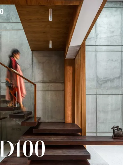A view of the Bansal Residence, an AD100 project from 2020. The space is defined by the interplay of raw concrete and warm wood, with a floating staircase creating a sense of lightness and movement.