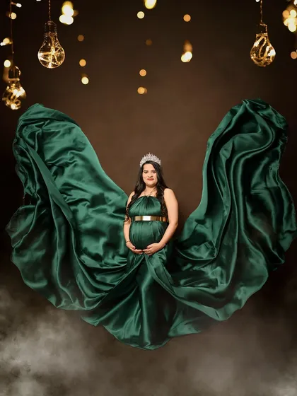 This emerald green satin gown looks absolutely stunning against a dark, moody backdrop with glowing lights. The fabric toss creates a sense of majestic power and elegance.