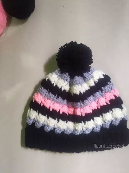 The Dolci Beanie is all about texture and color. I combined black, white, grey, and pink yarn to create this fun, striped beanie with a large black pom-pom on top.