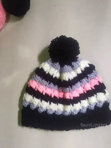 The Dolci Beanie is all about texture and color. I combined black, white, grey, and pink yarn to create this fun, striped beanie with a large black pom-pom on top.
