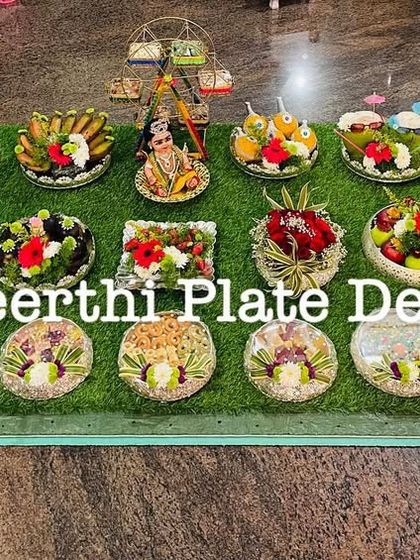 An extensive 25-plate setup for an ear-piercing ceremony in Ooty. The platters are filled with a variety of sweets, savories, and flowers, creating a beautiful and abundant display.