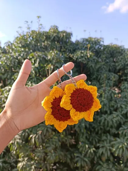 Holding up two of my classic sunflower keychains. This design is consistently one of my top sellers for wholesale clients.