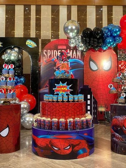 The main dessert table for the Spider-Man party, with a multi-tiered cake, themed cupcakes, and large character backdrops creating a stunning centerpiece.