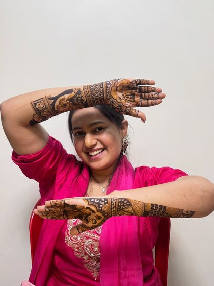 A joyful bride showing off her intricate Radha Krishna mehndi. Her smile says it all.