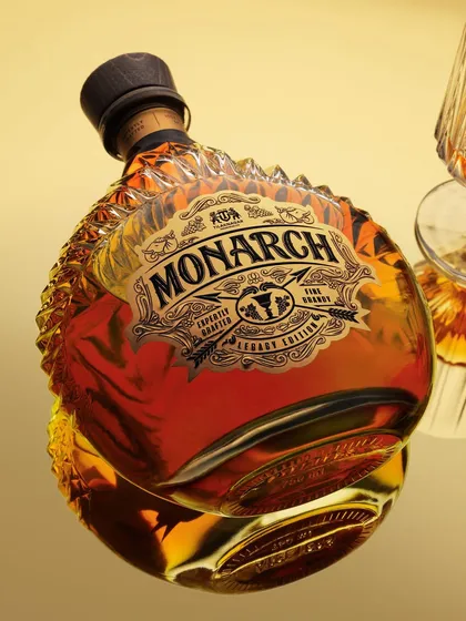An angled shot of the Monarch bottle on a reflective surface. The reflection adds depth and elegance, while the lighting is carefully controlled to show off the bottle's unique, ridged shape.