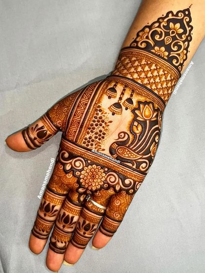 A beautiful back-of-hand design with a peacock and lotus as the main features. The hanging jhumkas add a touch of festive charm.