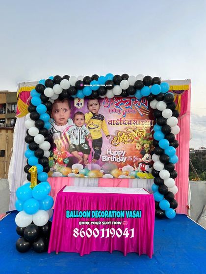 A simple and sweet first birthday setup on a terrace. The decoration includes a balloon arch over a custom photo banner.