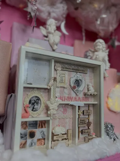 The centerpiece of this baby gift is a custom shadow box frame, filled with photos, birth details, and tiny mementos. It's a keepsake the family can cherish forever.