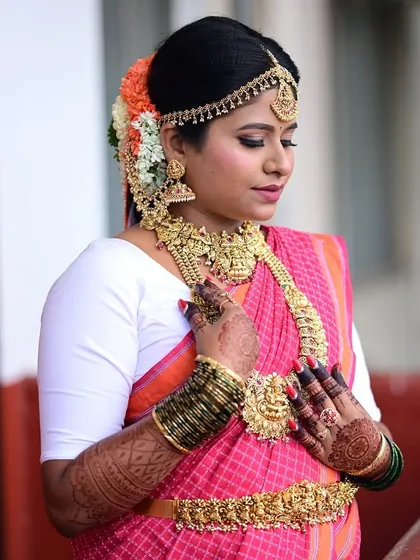 Our client Pavithra looks absolutely regal in this complete bridal look. She is wearing a full temple jewellery set, including a matha patti, choker, layered haram, and a detailed vaddanam, creating a truly majestic appearance.