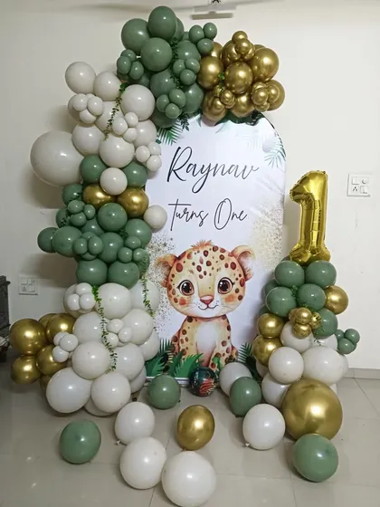 This "Wild One" safari theme is one of my most popular requests for first birthdays. I use a stylish palette of sage green, white, and gold chrome balloons to create a full arch around a personalized backdrop, complete with a cute leopard cub illustration and a number '1' balloon tower.