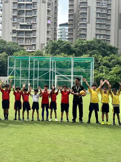 The boys' football teams and their coach celebrate together after a competitive tournament. These moments of shared joy build lasting bonds and reinforce the importance of teamwork.