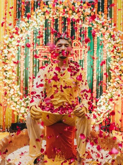 A beautiful final shot of the groom being showered with red rose petals after the haldi and milk rituals are complete.