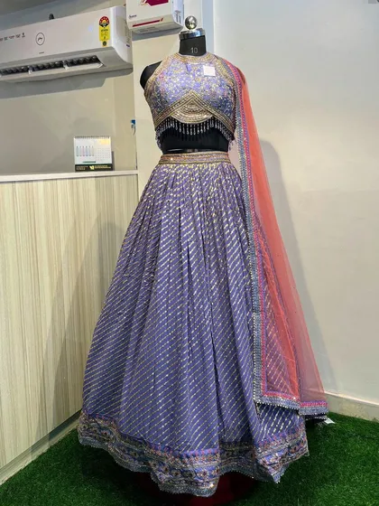 A front view of the purple lehenga, showing the embellished halter blouse and the flowy skirt. It's paired with a contrasting pink dupatta.